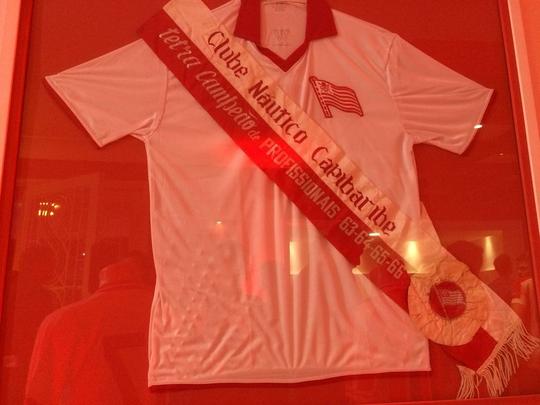 Espao na sede do clube traz um memorial relembrando os 115 anos de histria do Nutico, com antigas camisas e relquias alvirrubras; enquanto novos uniformes mantiveram a tradio das camisas timbus